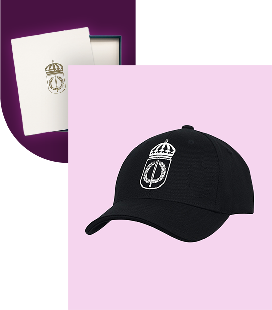 Svart keps med F&ouml;rsvarsh&ouml;gskolans vita logotyp. Guldlogotyp p&aring; vitt papper baktill.